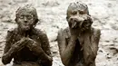 Dua orang anak bermian lumpur saat perayaan Mud Day di Nankin Mills Park di Westland, Michigan, AS (11/7). (AFP Photo/Jeff Kowalsky)