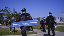 Petugas polisi membawa spanduk yang menunjukkan jarak sosial untuk mencegah penyebaran virus corona kepada pengunjung di sebuah taman di Hong Kong, Sabtu (2/1/2021). Varian baru virus corona telah menginfeksi dua siswa yang kembali ke Hong Kong dari Inggris. (AP Photo/Vincent Yu)
