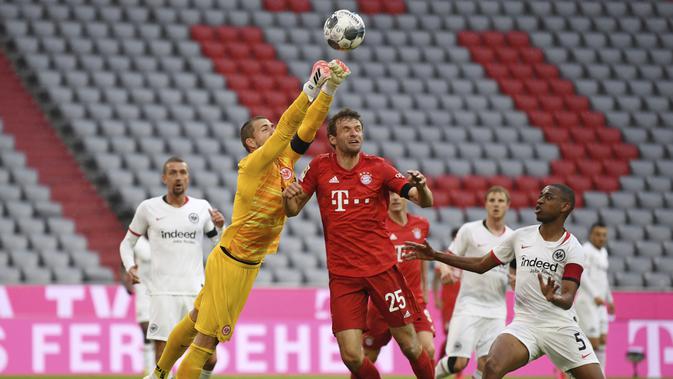 Pemain Bayern Munchen, Thomas Muller, berebut bola dengan kiper Eintracht Frankfurt, Kevin Trapp, pada laga Bundesliga di Allianz Arena, Minggu (24/5/2020). Bayern Munchen menang 5-2 atas Eintracht Frankfurt. (AP/Andreas Gebert)