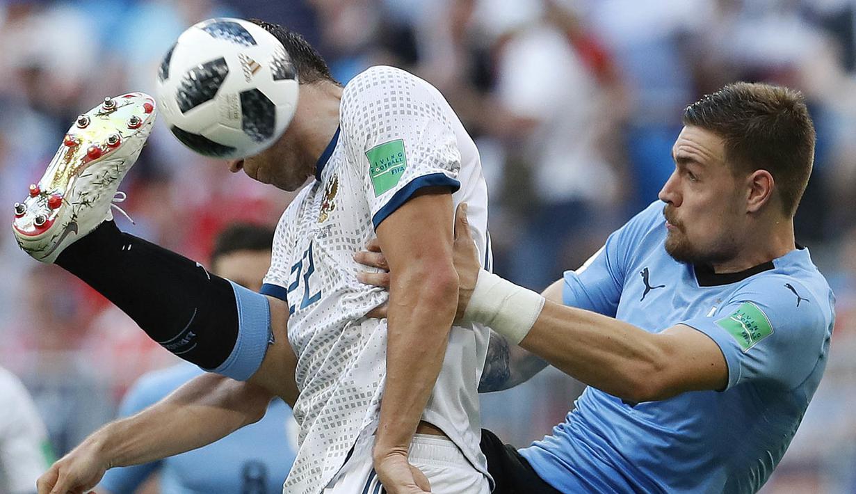 Pemain Uruguay, Sebastian Coates (kanan) menghalau bola dari sundulan pemain Rusia, Artyom Dzyuba pada laga grup A Piala Dunia 2018 di Samara Arena, Samara, Rusia, (25/6/2018). Uruguay menang 3-0. (AP/Hassan Ammar)