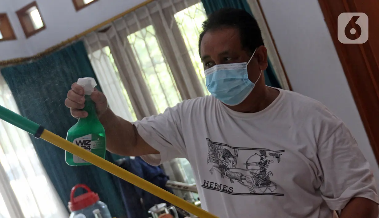 Suami NY, perempuan yang sedang melakukan isolasi mandiri karena terjangkit COVID-19, membersihkan peralatan usai memberikan makanan kepada sang istri di kediamannya, Rabu (10/2/2021). (Liputan6.com/Herman Zakharia)