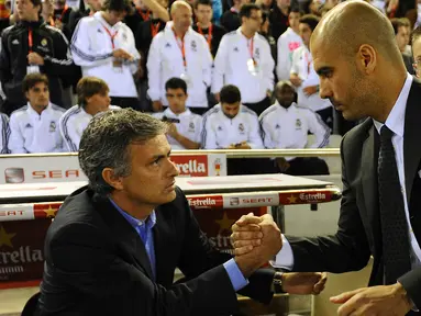 Pelatih asal Portugal Jose Mourinho (kiri) berjabat tangan dengan pelatih Barcelona Josep Guardiola sebelum pertandingan final Piala Spanyol Real Madrid melawan Barcelona di Stadion Mestalla di Valencia pada 20 April 2011. (AFP PHOTO/Lluis GENE)