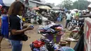 Seorang perempuan berbelanja di pasar Kaporo di Conakry, Guinea, Senin (13/9/2021). Pasukan elit militer Guinea melakukan kudeta dan menangkap Presiden Alpha Conde pada Minggu, 5 September lalu. (AP Photo/ Sunday Alamba)