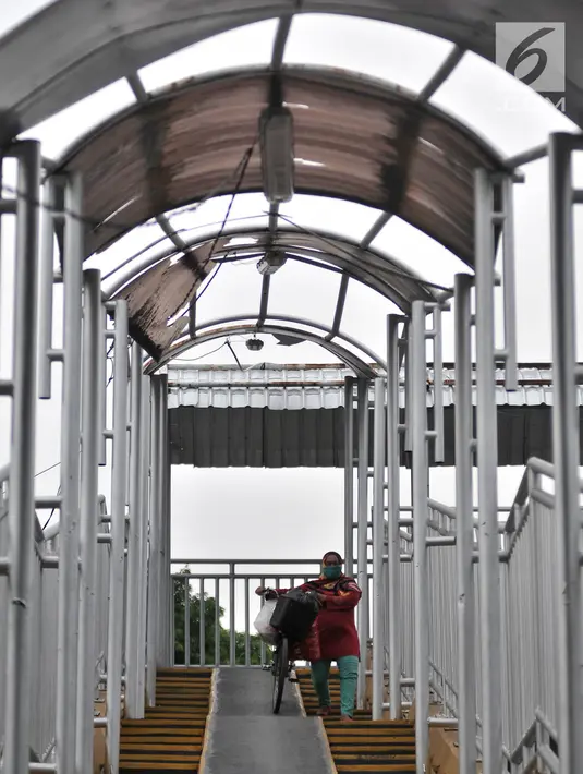Pejalan kaki melintasi jembatan penyeberangan orang (JPO) di Jalan Yos Sudarso, Jakarta, Kamis (8/11). JPO mengalami kerusakan pada bagian atap yang jebol. (Merdeka.com/Iqbal Nugroho)