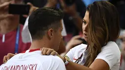 Kapten Polandia, Robert Lewandowski dihibur istrinya, Anna Lewandowska seusai dikalahkan Senegal pada pada penyisihan grup H di Piala Dunia 2018 di Stadion Spartak, Moskow, Selasa (19/6). Meski lebih diunggulkan, Polandia kalah 1-2. (FRANCK FIFE/AFP)