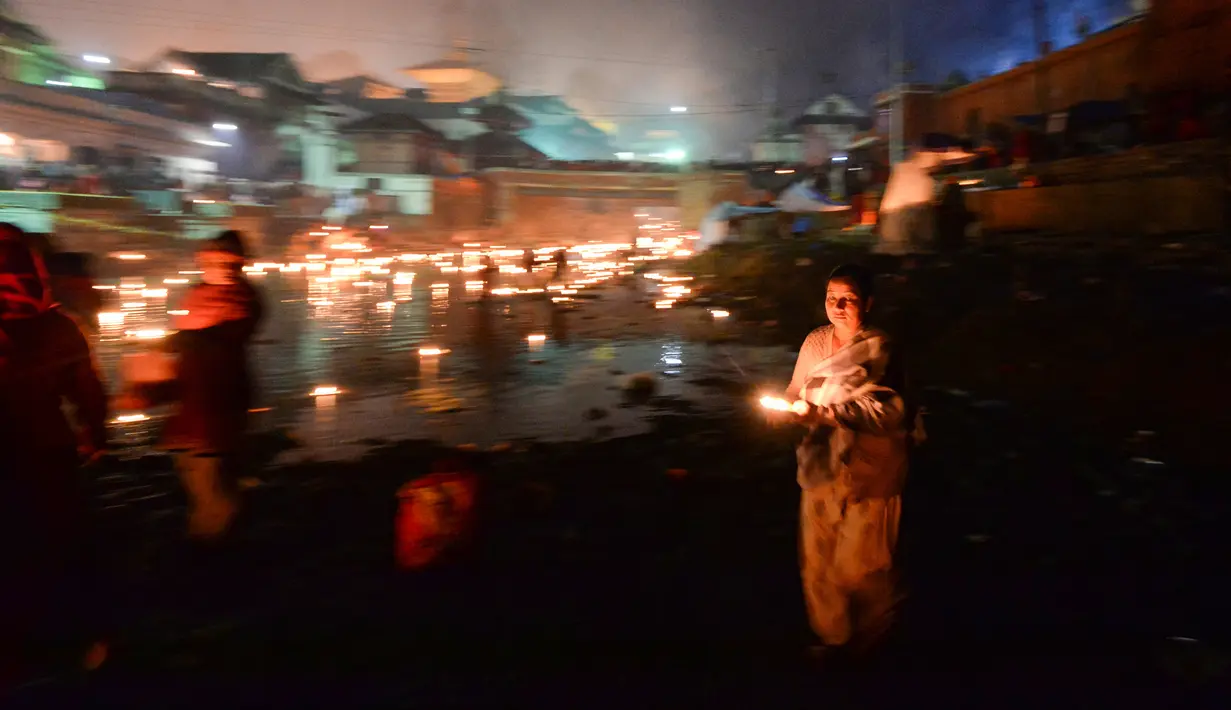 Seorang wanita membawa lampu minyak selama festival Bala Chaturdashi di Kuil Pashupatinath di Kathmandu (6/12). Festival Bala Chaturdashi ini dirayakan untuk mengenang anggota keluarga yang telah tiada. (AFP Photo/Prakash Mathema)