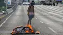 Seorang demonstran berdiri dekat kobaran api saat demonstrasi menuntut pengunduran diri Presiden Nicolas Maduro di Caracas, Venezuela, Sabtu (2/2). (AP Photo/ Fernando Llano)