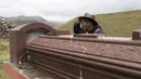 Gembala alpaka Esteban Taipe memeriksa sebuah makam di pemakaman kota hantu Santa Barbara, Peru, Sabtu (4/12/2021). Taipe telah menjadi pemandu wisata tidak resmi kota yang memiliki hampir 200 bangunan terbengkalai. (AP Photo/Franklin Briceño)
