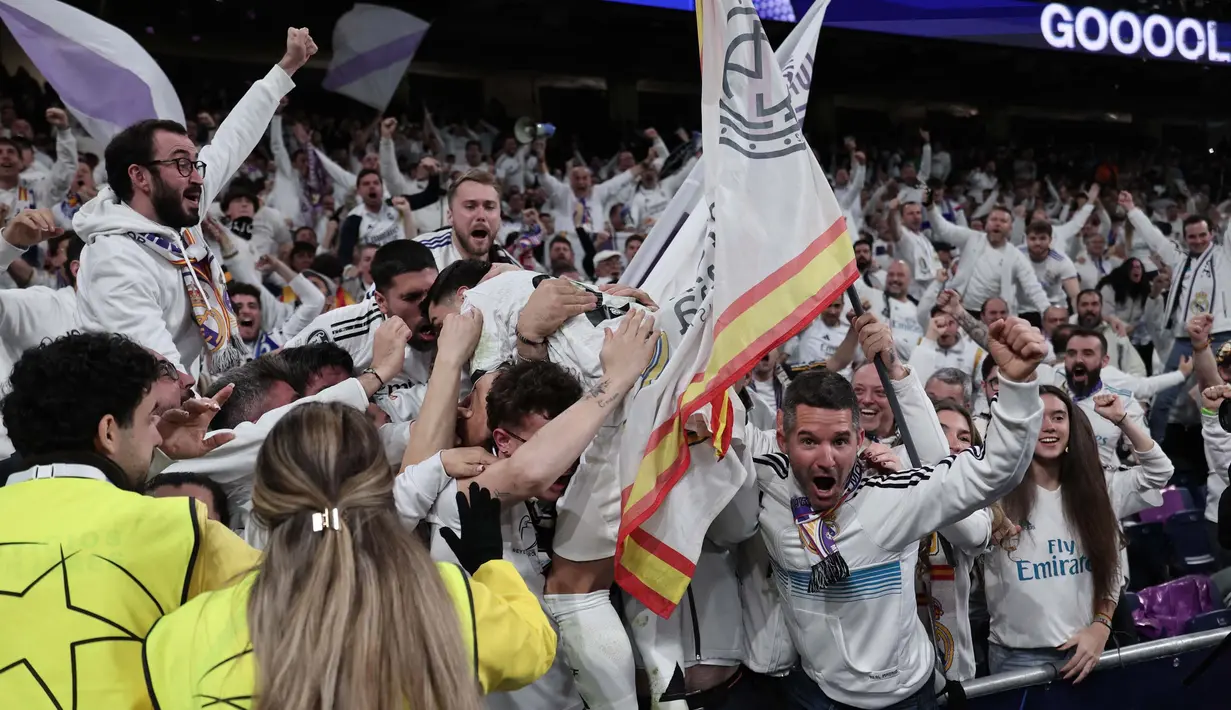 Penyerang Real Madrid, Brahim Diaz melompat ke tribun penonton setelah mencetak gol kedua bagi timnya pada pertandingan leg pertama 16 besar Liga Champions 2024/2025 melawan Atletico de Madrid di stadion Santiago Bernabeu, Madrid, pada 4 Maret 2025 waktu setempat atau Rabu (5/3/2025) dini hari WIB. (Thomas COEX/AFP)