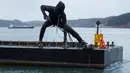 Patung perunggu terbesar di Inggris,  berjudul 'Messenger' tiba dengan tongkang di pesisir pantai Plymouth, Senin (18/3). Patung perunggu tersebut diciptakan oleh seorang pematung berusia 44 tahun bernama Joseph Hillier. (REUTERS/Peter Nicholls)