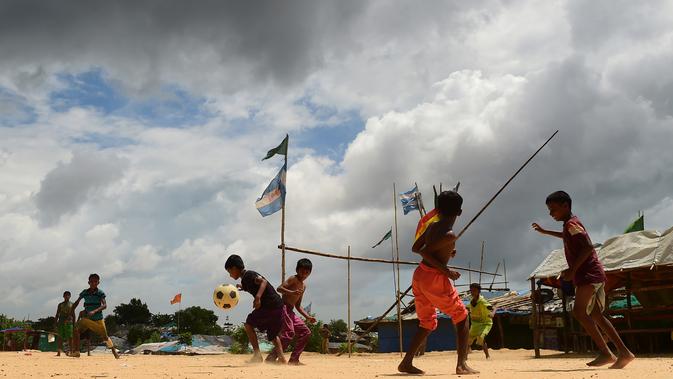 Anak-anak Rohingya bermain sepak bola di kamp pengungsi Kutupalong di Ukhia, Bangladesh, 19 Juli 2018. Bendera Argentina dan Brasil bahkan masih berkibar berdampingan dengan bendera Bangladesh di kamp pengungsi terbesar di dunia. (AFP/Munir UZ ZAMAN)
