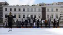 Orang-orang yang memakai masker mendengarkan pelatih ice skating di arena depan Balai Kota Athena, Kamis (23/12/2021). Yunani membatalkan konser Natal dan acara lainnya sebagai bagian dari pembatasan baru yang mencakup mandat penggunaan masker di luar ruangan. (AP Photo/Thanassis Stavrakis)