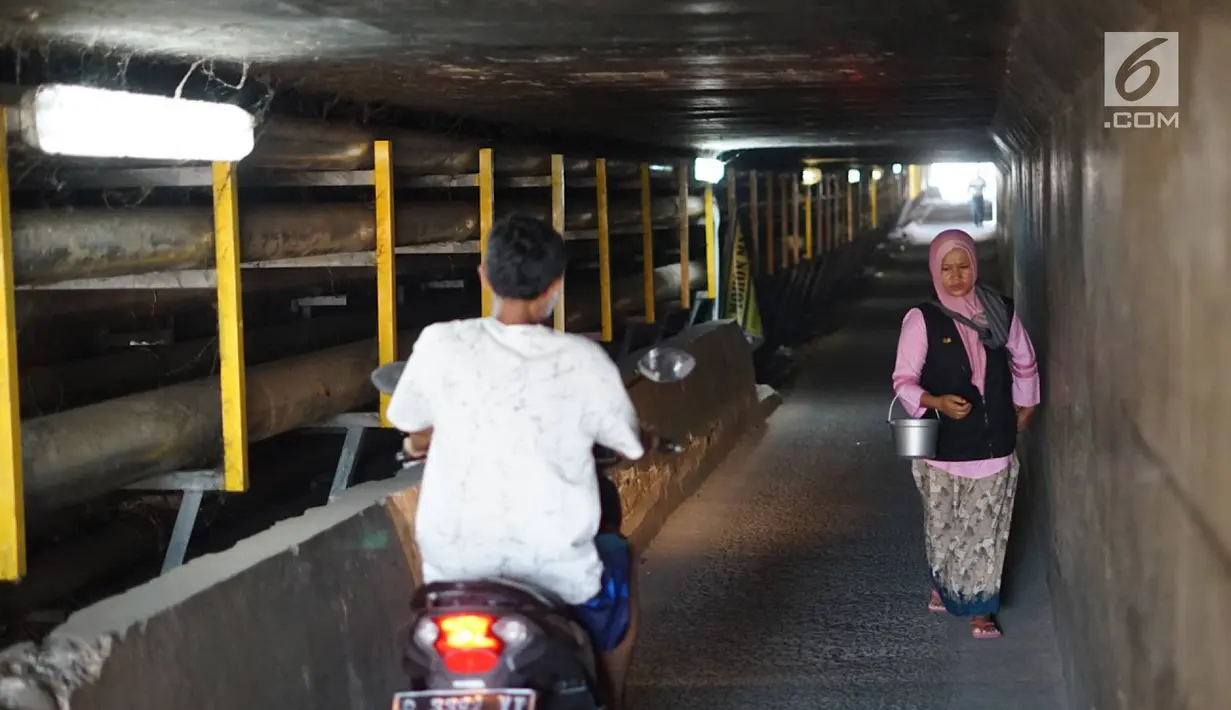 Pengedara motor serta pejalan kaki melintasi terowongan di bawah Jalan Tol Jagorawi, Kampung Rambutan, Jakarta, Rabu (21/8/2019). Meskipun sempit dan gelap, terowongan itu menjadi akses alternatif pengguna jalan menyeberangi Jalan Tol Jagorawi di kawasan tersebut. (Liputan6.com/Immanuel Antonius)