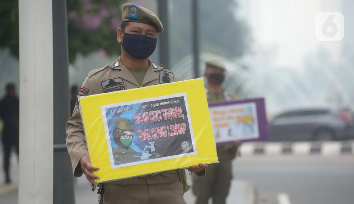 Petugas Satpol PP memegang poster himbauan kepada masyarakat tentang Covid-19, Jakarta, Jumat (6/11/2020). Upaya pemerintah tidak berhenti mengingatkan masyarakat untuk selalu mengenakan masker dan 3M agar terhindar dari bahaya penyebaran Covid-19 yang kini belum berakhir. (merdeka.com/Imam Buhori)