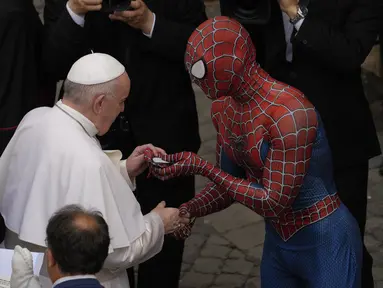 Paus Fransiskus bertemu Spider-Man, yang memberinya masker, pada akhir audiensi umum mingguan dengan jumlah umat terbatas di San Damaso Courtyard, Vatikan, Rabu (23/6/2021). Pria itu adalah Mattia Villardita (27) dari Italia utara yang menghibur anak-anak di rumah sakit. (AP Photo/Andrew Medichini)