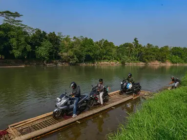 Warga bersama sepeda motornya menyeberangi Sungai Cisadane menggunakan rakit bambu di kawasan Ciseeng, Kabupaten Bogor, Jawa Barat, Kamis (11/6/2026). (merdeka.com/Arie Basuki)