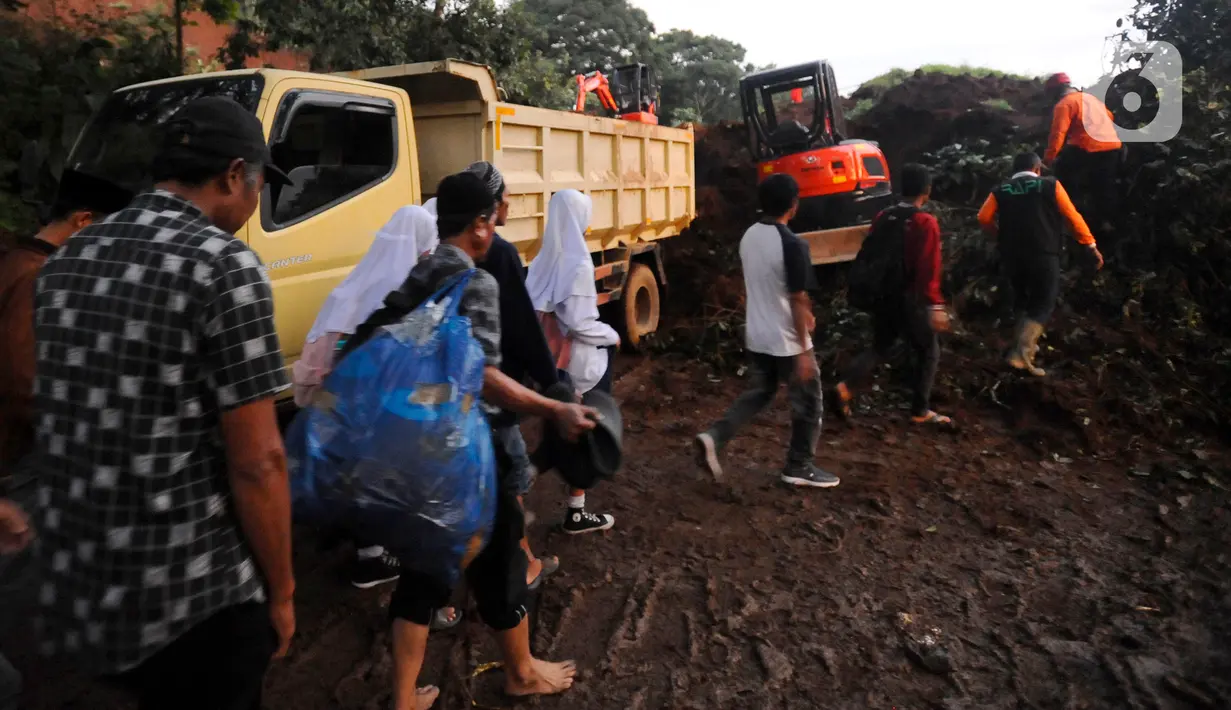 Warga melewati longsor yang menutup ruas jalan utama Cipanas-Cianjur akibat gempa bumi di kawasan Cugenang, Cianjur, Jawa Barat, Senin (21/11/2022). Longsor membawa sebuah angkot yang diduga berisi penumpang dan truk ke dalam jurang, evakuasi pun akan dilanjutkan esok hari. (merdeka.com/Arie Basuki)