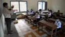 Siswa duduk di kelas dengan menjaga jarak saat memperhatikan guru mereka mengajar ketika sekolah dibuka kembali di Phnom Penh, Senin (7/9/2020). Sekolah-sekolah di Kamboja dibuka kembali pada Senin (7/9) setelah enam bulan ditutup akibat COVID-19. (TANG CHHIN Sothy /AFP)
