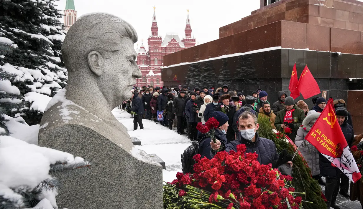 Pendukung komunis meletakkan bunga di makam pemimpin Soviet Josef Stalin menandai peringatan 142 tahun kelahirannya di dekat Tembok Kremlin di Lapangan Merah dengan makam Lenin di sebelah kanan, di Moskow, Rusia, Selasa (21/12/2021). (AP Photo/Alexander Zemlanichenko)