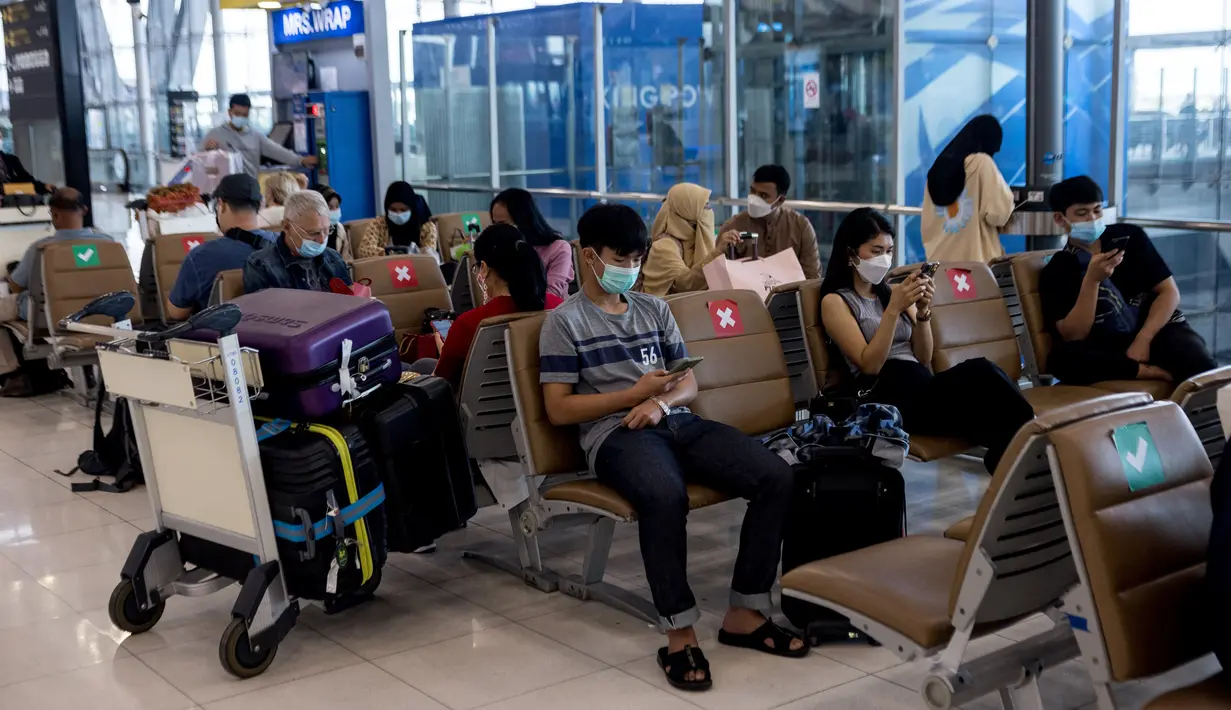Penumpang menunggu dengan barang bawaan mereka di Bandara Suvarnabhumi di Bangkok, saat Thailand melanjutkan skema perjalanan bebas karantina untuk pelancong yang divaksinasi, Selasa (1/2/2022). Program ini sebelumnya ditangguhkan karena melonjaknya kasus Covid-19 di Thailand. (Jack TAYLOR/AFP)