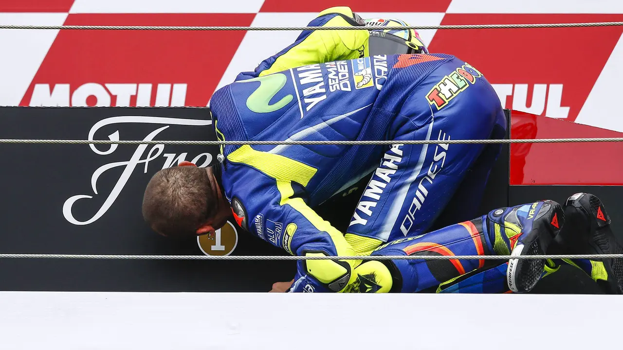 Pembalap Movistar Yamaha, Valentino Rossi, mencium podium usai menjadi yang tercepat pada MotoGP Belanda 2017 di Sirkuit Assen, Minggu (25/6/2017). Riders asal Italia itu memiliki catatan waktu 41 menit 41,149 detik. (AFP/Vincent Jannink) 