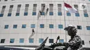 Pengendara motor melintas di bawah pekerja yang tengah melakukan perawatan gedung perkantoran di kawasan Sudirman, Jakarta, Senin (30/11/2020). (merdeka.com/Iqbal S. Nugroho)
