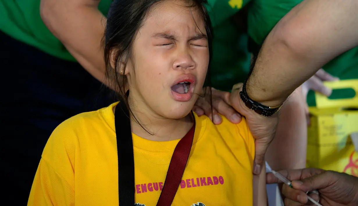 Ekspresi seorang siswi saat disuntikkan vaksin anti-dengue di Sekolah Dasar Parang di Marikina, sebelah barat Manila, Senin (4/4). Filipina telah menyuntikkan vaksin pertama di dunia untuk penyakit DBD itu kepada 1 juta pelajar. (NOEL CELIS/AFP)