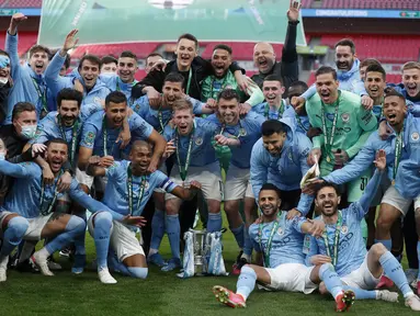 Para pemain Manchester City berpose dengan trofi merayakan kemenangan atas Tottenham Hotspur pada pertandingan final Piala Liga Inggris di stadion Wembley di London, Senin (26/4/2021). City menang tipis atas Tottenham dengan skor 1-0. (AP Photo/Alastair Grant)