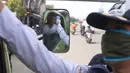 Petugas memeriksa suhu tubuh pengemudi truk saat pelaksanaan Pembatasan Sosial Berskala Besar (PSBB) di kawasan Gading Serpong, Tangerang Selatan, Sabtu (18/4/2020). Pengukuran suhu tubuh tersebut merupakan cek point dari PSBB yang baru saja diberlakukan di Tangerang Raya (Liputan6.com/Angga Yuniar)