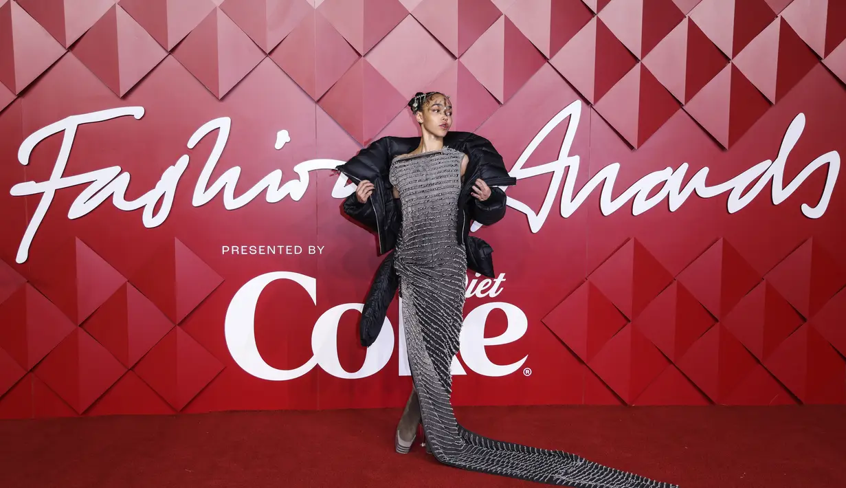 FKA Twigs berpose untuk fotografer setibanya di British Fashion Awards di London, Senin, 5 Desember 2022. FKA Twigs tampil dengan gaun panjang lantai abu-abu arang yang mengikuti di belakangnya dengan jaket berlapis hitam dengan jaket empuk hitam besar yang memiliki kerah kerah besar dan cocok dengan keunikan riasan di wajahnya. (Photo by Vianney Le Caer/Invision/AP)