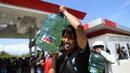 Korban gempa dan tsunami membawa bahan bakar minyak (BBM) di SPBU Kota Palu, Sulawesi Tengah, Senin (1/10). Sebelumnya, warga nekat menjarah BBM yang tersisa di dalam mobil tangki milik Pertamina pada Sabtu, 29 September 2018. (Jewel Samad/AFP)