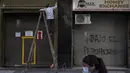 Seorang pria membersihkan fasad etalase penukaran uang di pusat kota Santiago, Chile, Sabtu (12/6/2021). Ibu kota Chile telah mengembalikan tindakan karantina di tengah meningkatnya kasus COVID-19, meskipun hampir 60% warga negara itu sudah divaksinasi sepenuhnya. (AP Photo/Esteban Felix)