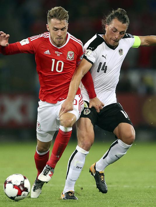 Pemain Wales, Aaron Ramsey (kiri) berebut bola dengan pemain Austria, Julian Baumgartlinger pada laga Group D kualifikasi Piala Dunia 2018 di Cardiff City Stadium, Cardiff, (2/8/2017). Wales menang 1-0. (David Davies/PA via AP)