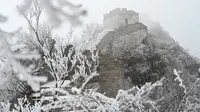 Tembok Besar China terlihat setelah hujan salju ringan di Jiankou, utara Beijing pada Minggu (9/1/2022). Jalur pada Tembok Besar China itu pun terlihat memutih akibat salju. (GREG BAKER / AFP)