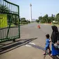 Sejumlah warga berjalan di depan kawasan Monumen Nasional (Monas), Jakarta, Minggu (26/7/2020). Sejumlah warga mulai mengunjungi kawasan Monas meski masih ditutup sementara di masa PSBB transisi. (Liputan6.com/Faizal Fanani)