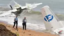 Petugas forensik Prancis melintas di dekat lokasi jatuhnya pesawat kargo Antonov yang menewaskan 4 orang warga Moldovan akibat dihantam ombak besar di Abidjan (14/10). Pesawat yang disewa Tentara Prancis membawa 10 penumpang. (AFP PHOTO / Issouf Sanogo)