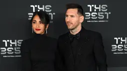 Pemain Paris Saint-Germain asal Argentina, Lionel Messi (kanan) dan istrinya Antonela Roccuzzo berpose setibanya pada acara The Best FIFA Football Awards 2022 di Paris, Prancis, 27 Februari 2023. Antonella menenteng tas merah mawar, senada dengan warna lipstik yang menghiasi bibirnya. (FRANCK FIFE/AFP)