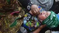 Tenaga kesehatan memberikan vaksin polio kepada seorang balita selama kampanye vaksinasi di kawasan tua Kabul, Afghanistan pada 8 November 2021. Vaksinasi tersebut merupakan yang pertama sejak Taliban berkuasa di Afghanistan. (WAKIL KOHSAR / AFP)