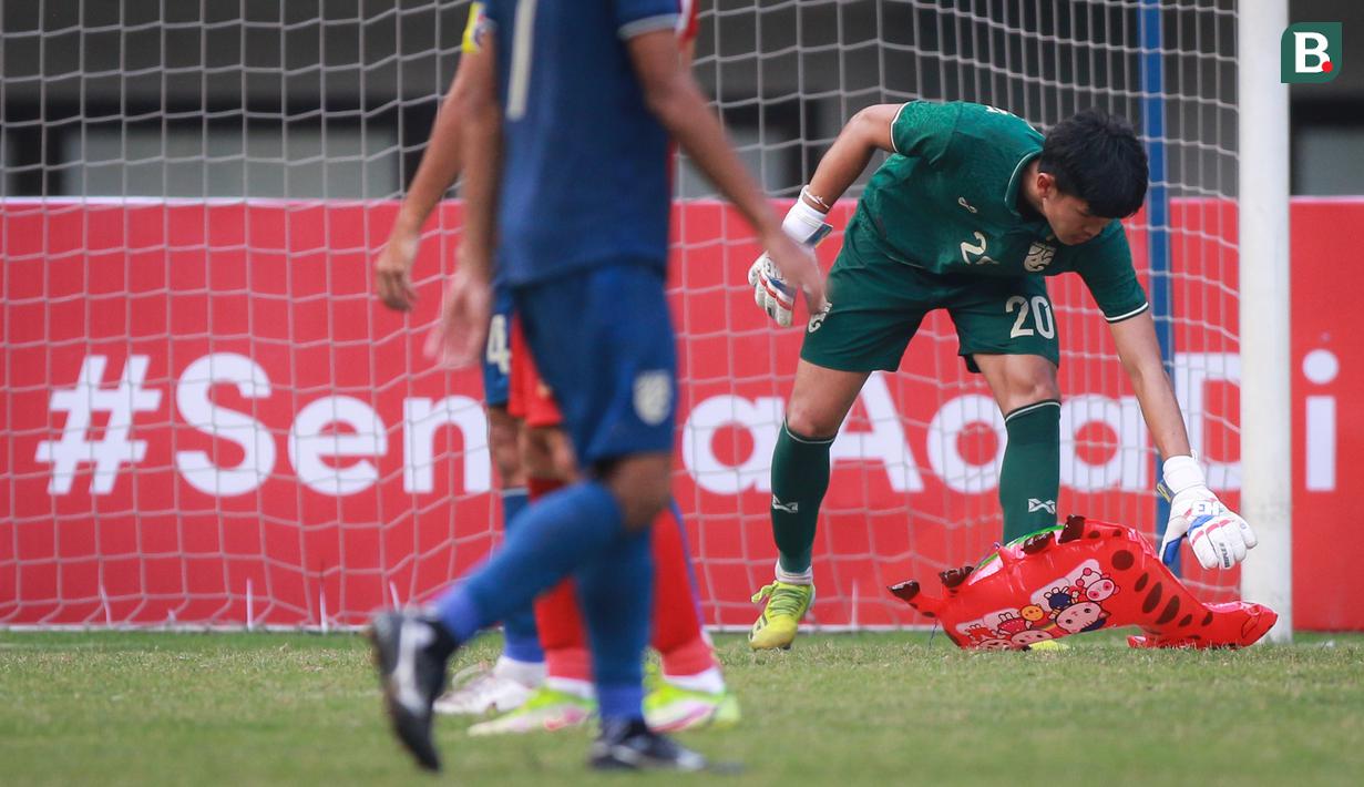 Kiper Timnas Thailand U-19, Chommaphat Boonloet memungut balon berbentuk jerapah yang memasuki lapangan pada laga perebutan juara ketiga Piala AFF U-19 2022 antara Timnas Vietnam U-19 melawan Timnas Thailand U-19 di Stadion Patriot Candrabhaga, Bekasi (15/07/2022). (Bola.com/Bagaskara Lazuardi)