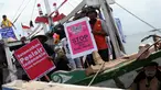 Sejumlah nelayan bersama aktivis Walhi menunjukkan poster berisi penolakan terhadap proyek reklamasi Teluk Jakarta saat upacara sedekah bumi yang lebih dikenal dengan sebutan Nadran di Muara Angke, Jakarta, Minggu (13/12/2015). (Liputan6.com/Helmi Afandi)