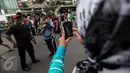 Pengunjung Car Free Day (CFD) tengah asik melilitkan ular ke badannya sementara temannya mengabadikan momen tersebut dengan kamera ponsel di kawasan Bundaran HI, Jakarta, Minggu (29/1). (Liputan6.com/Faizal Fanani)