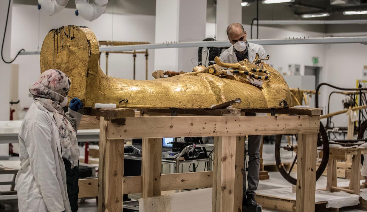 Para arkeolog merestorasi sarkofagus atau peti mati emas Firaun Tutankhamun di laboratorium restorasi Grand Egyptian Museum (GEM), Giza, Mesir, Senin (13/4/2020). Firaun Tutankhamun merupakan Raja Mesir Kuno yang memerintah antara tahun 1342-1325 SM. (Khaled DESOUKI AFP)