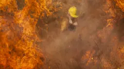 Petugas pemadam kebakaran memadamkan api di Capilla del Monte, Cordoba, Argentina (15/10/2020). Kebakaran diperburuk oleh kekeringan ekstensif yang dialami wilayah tersebut. (AP Photo/Mario Tizon)