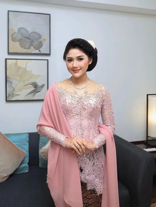 Kali ini, Erina Gudono tak kalah memesona dalam balutan kebaya berwarna merah muda yang lembut. Kebaya ini memiliki garis leher yang terbuka dengan brokat super cantik. Erina semakin cantik dengan selendang berwarna senada, riasan wajah natural yang pas, tatanan rambut, dan aksesorinya yang sempurna secara keseluruhan. Foto: Instagram.