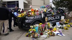 Warga meninggalkan karangan bunga di mobil polisi yang diparkir di luar Departemen Kepolisian Boulder setelah seorang petugas menjadi salah satu korban penembakan massal di toko King Soopers di Boulder, Colorado (23/3/2021). (AP Photo/David Zalubowski)