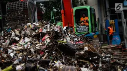 Petugas mengeruk sampah menggunakan alat berat di pintu air Manggarai, Jakarta, Selasa (4/12). Tingginya intensitas hujan di wilayah Jabodetabek membuat sampah yang terbawa arus sungai menumpuk di Pintu Air Manggarai. (Liputan6.com/Faizal Fanani)