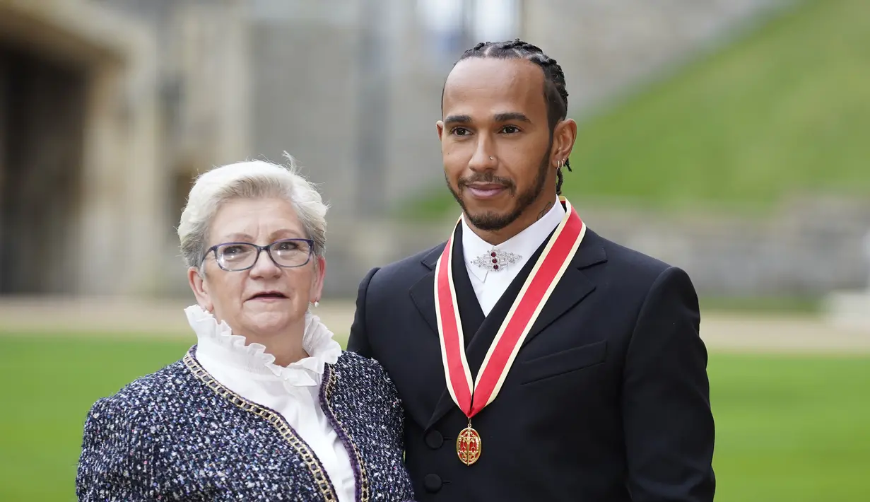 Pembalap Lewis Hamilton foto bersama dengan ibunya, Carmen Lockhart usai penobatannya sebagai Knight Bachelor oleh Pangeran Charles di Kastil Windsor di Windsor, Inggris, Rabu (15/12/2021). (Andrew Matthews/Pool Photo via AP)