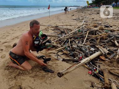 Seorang wisatawan mengumpulkan sampah yang berserakan di Pantai Kuta, Badung, Bali, Kamis (20/4/2023). (merdeka.com/Arie Basuki)