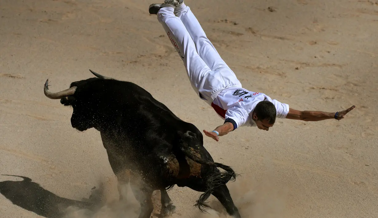Seorang recortador melompati serudukan banteng selama Festival San Fermin di Pamplona, Spanyol, Sabtu (9/7). Aksi akrobatik melompati serangan banteng ini dinamakan recortadores. (REUTERS / Vincent West)