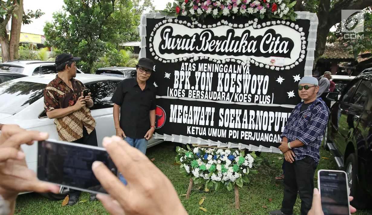 Pelayat berfoto didekat karangan bunga dari Ketua Umum PDI Perjuangan, Megawati Soekarnoputri untuk musisi Yon Koeswoyo yang berada di rumah duka di Pamulang, Tanggerang Selatan, Jumat (5/1). (Liputan6.com/Herman Zakharia)